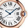 Close-up of the Cartier Ballon Bleu de Cartier watch, showcasing a white guilloché dial, black Roman numerals, blue hands, and a pink gold case with a crown set with a blue cabochon.