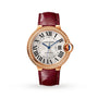 The Ballon Bleu de Cartier by Cartier features a round gold case, diamond bezel, Roman numerals, blue hands, and a vibrant red leather strap.