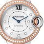 Close-up of the Ballon Bleu de Cartier watch by Cartier, featuring a diamond bezel, rose gold accents, silver dial with blue hands, Roman numeral XII at the top, and a crown set with a signature blue cabochon.