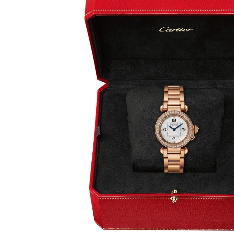 A Cartier Pasha de Cartier watch in rose gold with a round face and diamond bezel, beautifully presented in an open red Cartier box.