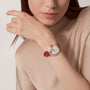 A woman in a beige top showcases the Ballon Bleu de Cartier watch by Cartier on her left wrist, featuring a red leather strap, rose gold case, and white dial.
