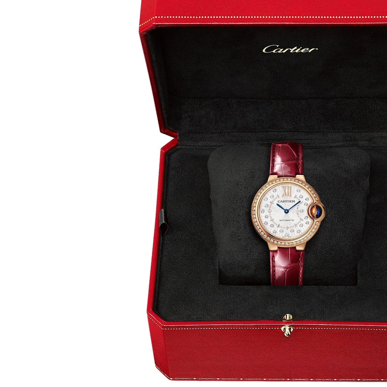 The Ballon Bleu de Cartier watch by Cartier features a diamond-encrusted face and rose gold accents on a red leather strap, elegantly displayed in an open red box lined with black fabric.