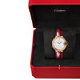 The Ballon Bleu de Cartier watch by Cartier features a diamond-encrusted face and rose gold accents on a red leather strap, elegantly displayed in an open red box lined with black fabric.