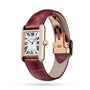 The Cartier Tank Louis Cartier watch features a rectangular rose gold case, diamond-set bezel, white dial with Roman numerals, blue hands, and a burgundy leather strap.