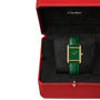 A Cartier Tank Louis Cartier watch with a green lacquer-effect dial, 18K yellow gold case, and matching green strap is shown in an open red Cartier box featuring a black interior.