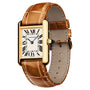 The Cartier Tank Louis Cartier features a rectangular yellow gold case, Roman numerals, blue hands, a sapphire cabochon crown, and a brown leather strap.