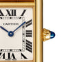 Close-up of the Cartier Tank Louis Cartier watch face with Roman numerals, blue hands, a yellow gold case, and a sapphire cabochon set in the crown.