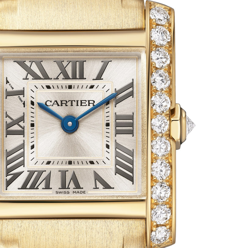 Close-up of the Cartier Tank Française watch, featuring a yellow gold case, Roman numerals, blue hands, and a brilliant-cut diamond-encrusted bezel on the right side of the face.
