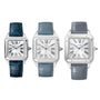 Three Cartier Santos-Dumont watches with silver square dials and blue leather straps are displayed side by side against a white background.