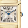 Close-up of the Cartier Tank Française watch, featuring a gold case, Roman numeral markers, blue hands, and a blue cabochon crown.