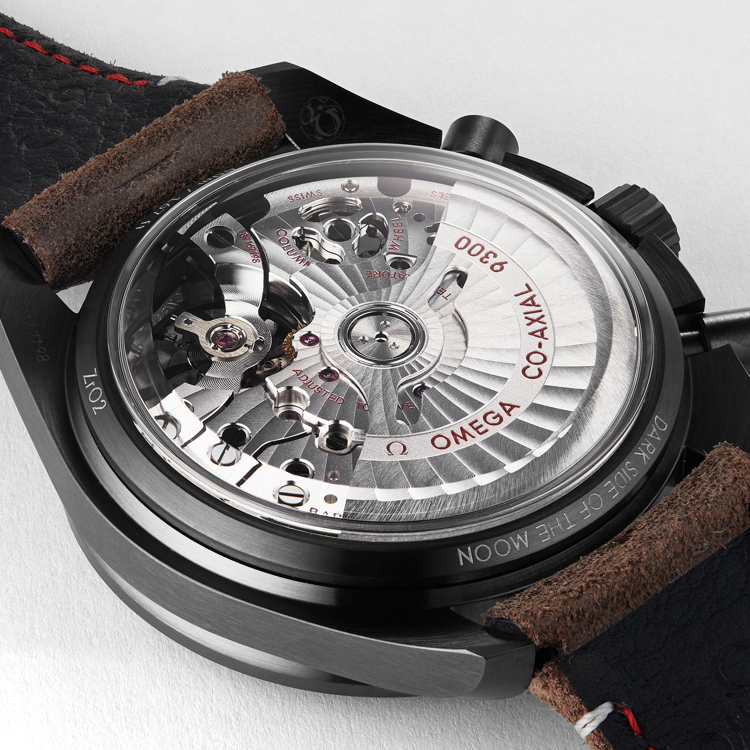 Close-up of the OMEGA Speedmaster Dark Side Of The Moon wristwatch, revealing its exposed 9300 calibre movement with “Co-Axial 9300” and “DARK SIDE OF THE MOON” engraved on the back.