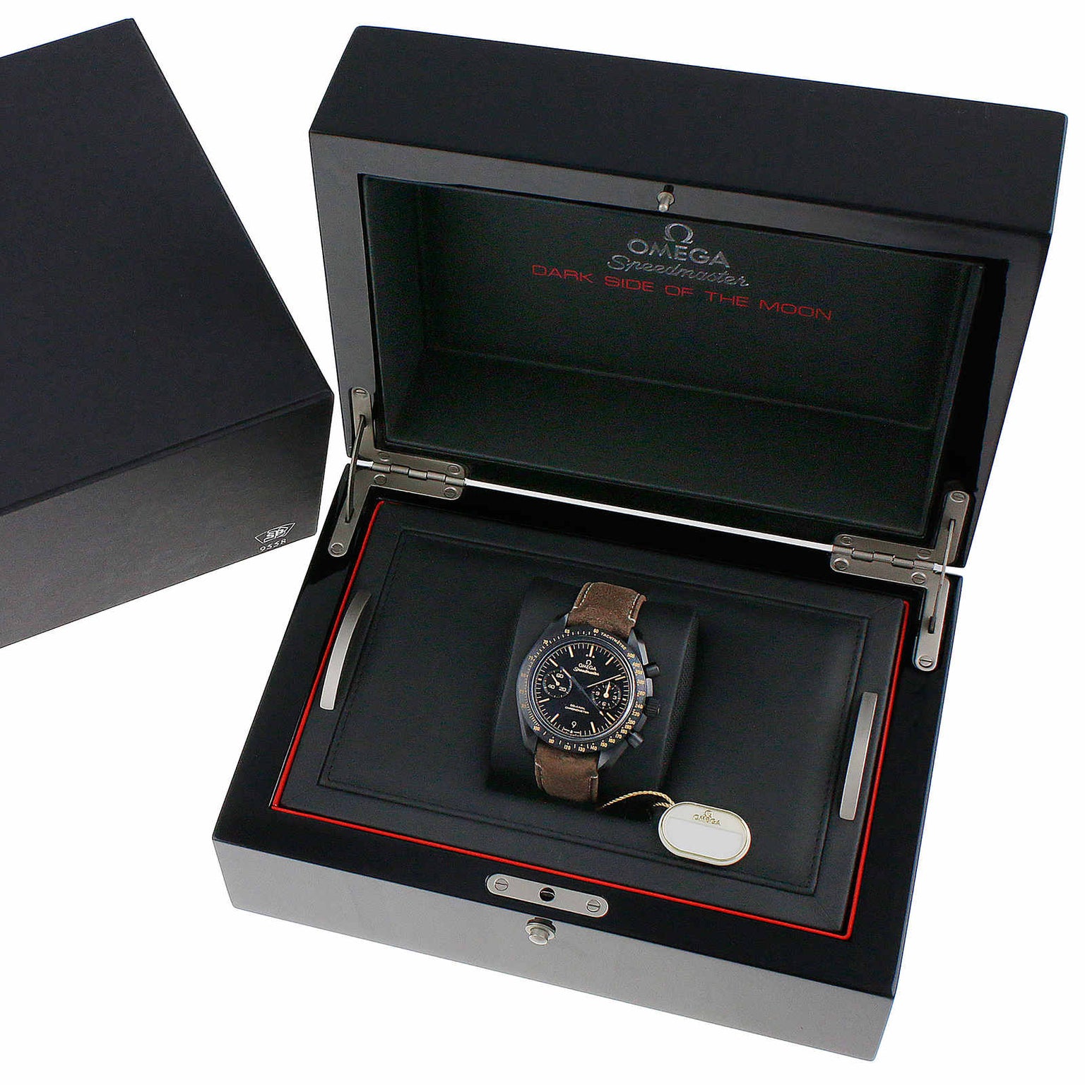 An OMEGA Speedmaster Dark Side of the Moon wristwatch with a brown strap and 9300 calibre movement is displayed in an open black presentation box.
