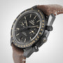 A close-up of the OMEGA Speedmaster Dark Side Of The Moon, featuring a black ceramic case, black dial, chronograph subdials, tan indices, and a brown leather strap.