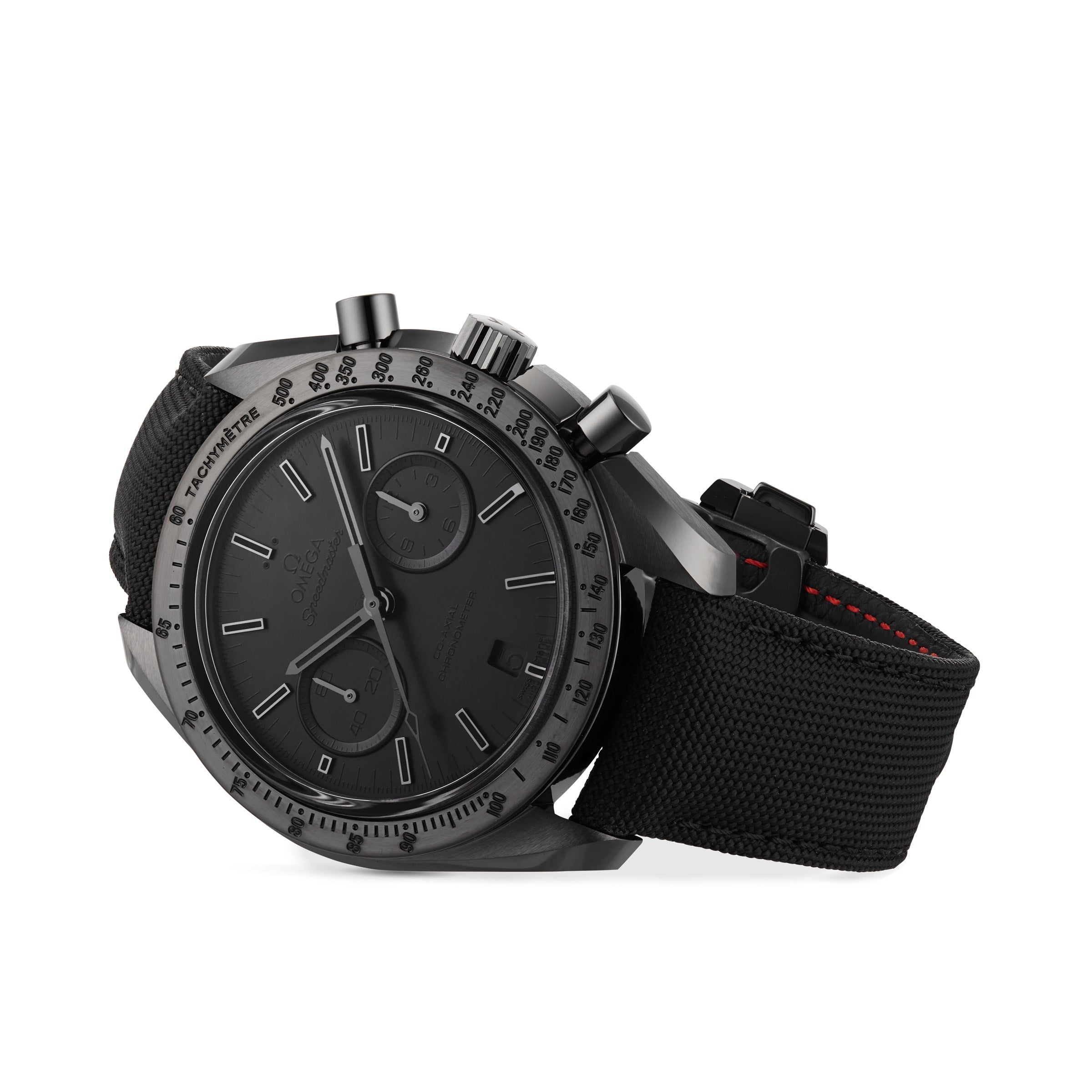 The OMEGA Speedmaster Dark Side of the Moon Black Black is a chronograph with a fabric strap, tachymeter bezel, two subdials, and minimalist hour markers, shown at an angle on white. Inspired by Apollo 8s Dark Side of the Moon.