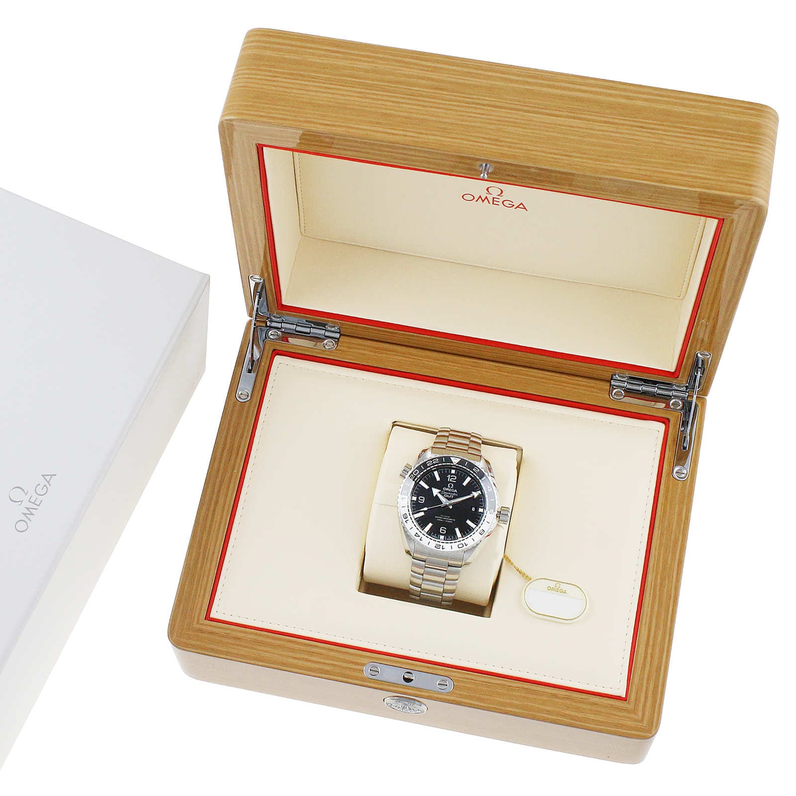 An OMEGA Seamaster Planet Ocean 600M with a metal band is shown in a wooden presentation box beside a white OMEGA branded box.