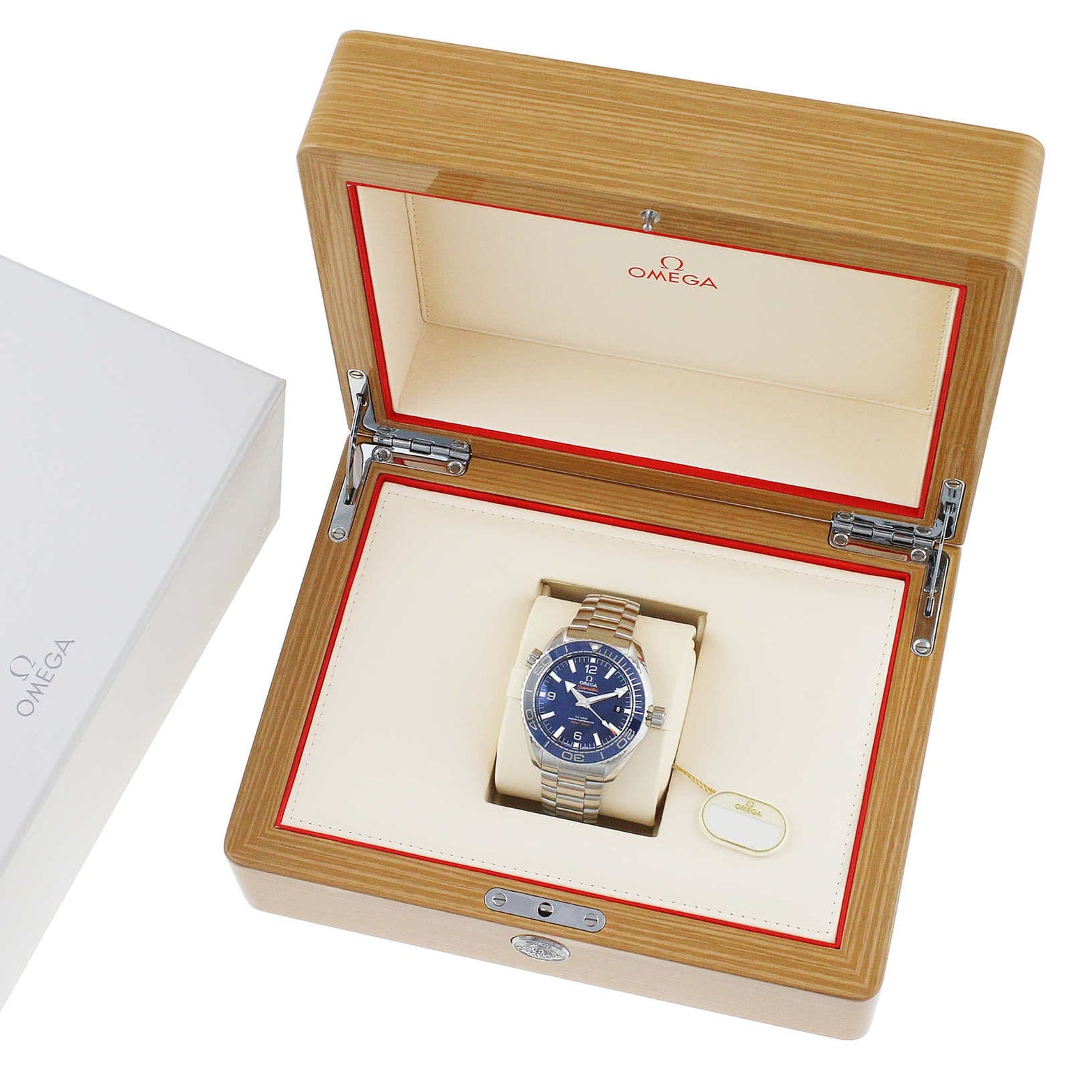 A silver OMEGA Seamaster Planet Ocean 600M dive watch with a blue face sits in an open wooden OMEGA box, highlighting its Master Chronometer certification.