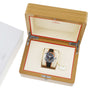 An OMEGA Seamaster Planet Ocean 600M dive watch with a black and orange strap is displayed in an open wooden OMEGA box with cream and red interior, next to a white OMEGA outer box.