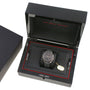 The OMEGA Speedmaster Dark Side of the Moon Meteorite luxury wristwatch, featuring a black strap and sleek ceramic case, is displayed in an open black presentation box with a removable tag beside it.