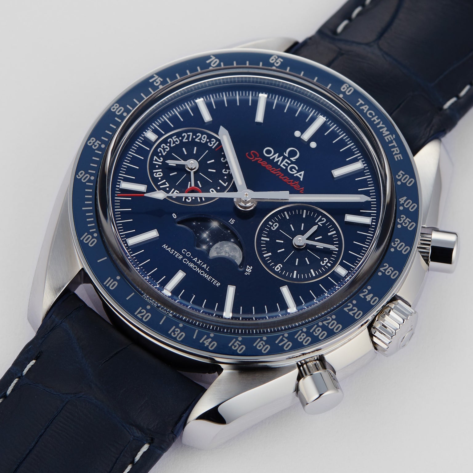 A close-up of the OMEGA Speedmaster Moonphase wristwatch showcases its blue dial, chronograph subdials, moonphase indicator, and an elegant blue leather strap.