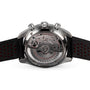 Close-up of the OMEGA Speedmaster Racing, highlighting its exposed Master Chronometer 9900 calibre movement and rotor through the caseback; the watch has a black perforated strap with red accents.