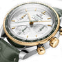 Close-up of the OMEGA Speedmaster 38 wristwatch with a white dial, green bezel, gold details, and green leather strap. Features three subdials, a tachymeter scale, and a Co-Axial movement inspired by lunar missions.