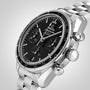 An OMEGA Speedmaster 38 watch in stainless steel with a black dial, tachymeter bezel, and three subdials, displayed on a silver metal bracelet—part of the acclaimed Speedmaster collection.