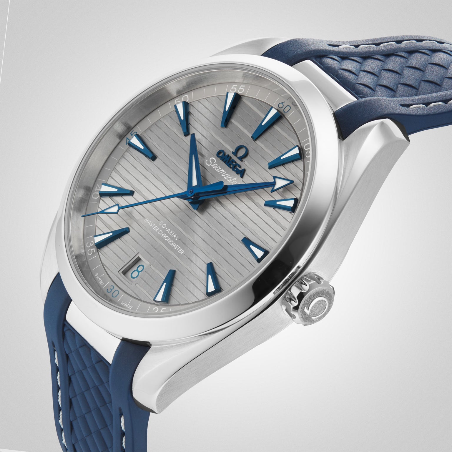 The OMEGA Seamaster Aqua Terra 150M wristwatch with a patterned silver face, blue hour markers, and a blue rubber strap is displayed on a light gray background.