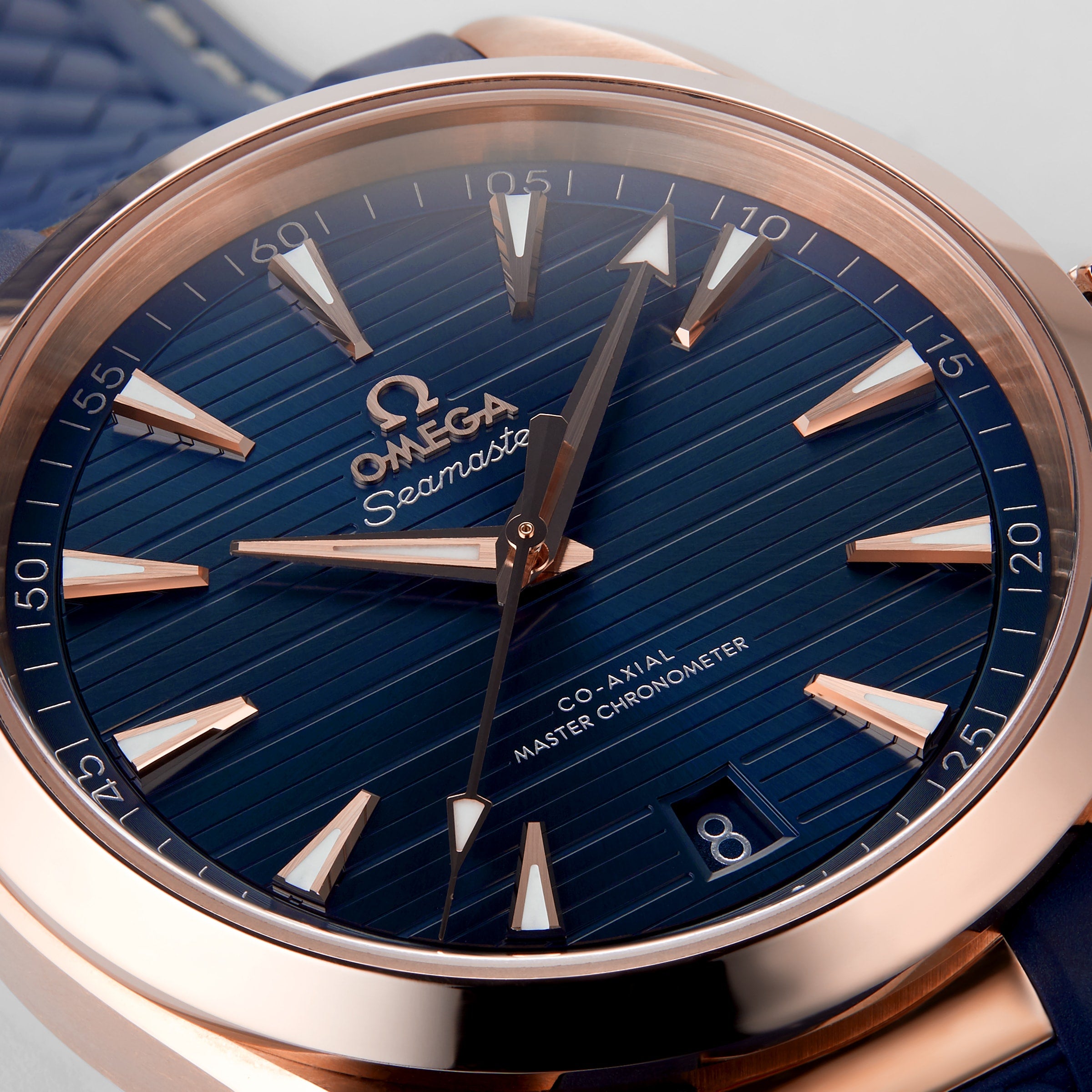 Close-up of the OMEGA Seamaster Aqua Terra 150M featuring a blue textured dial, gold hour markers and hands, date window at 6 o’clock, and a Master Chronometer-certified 8800 calibre movement.