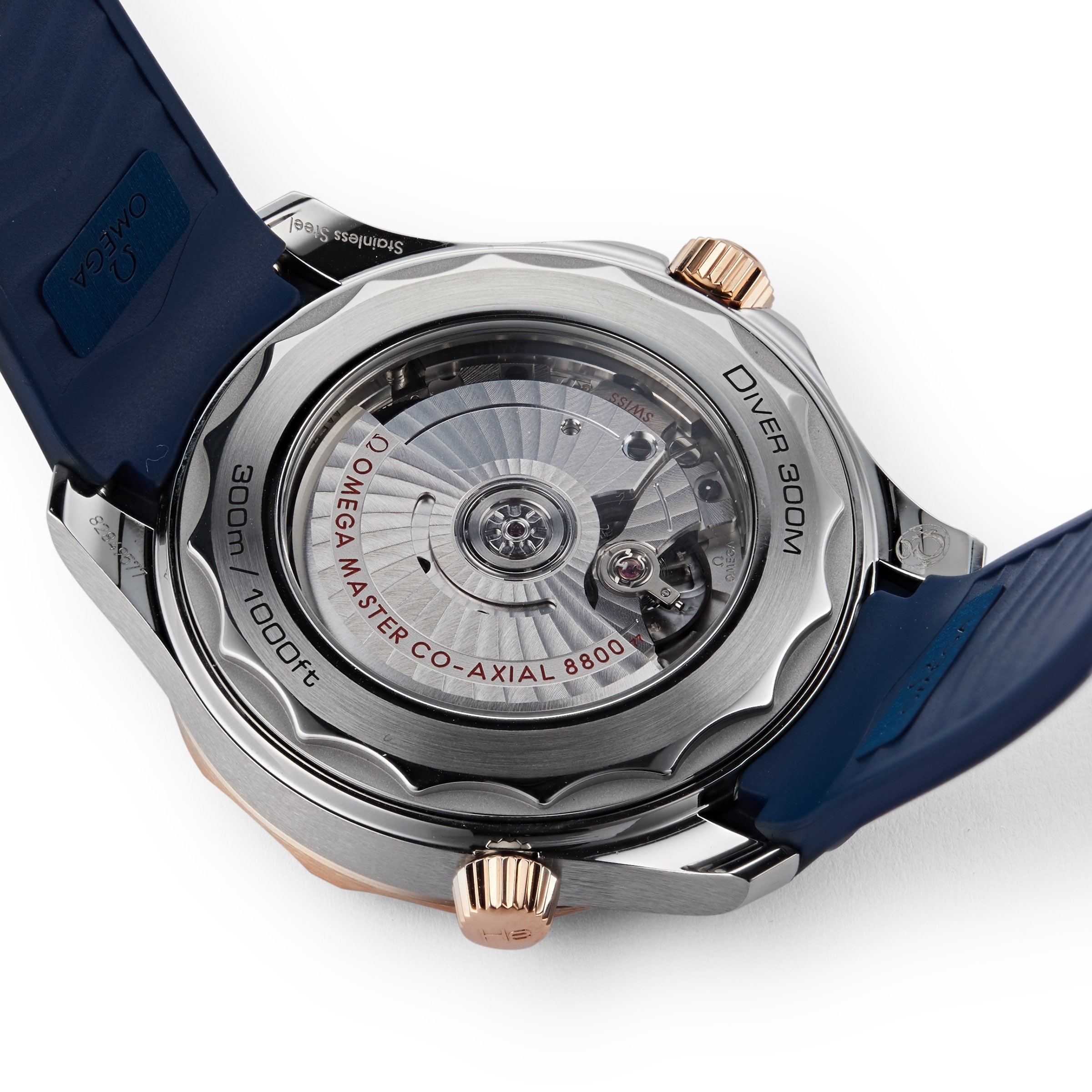 A close-up of the OMEGA Seamaster Diver 300M case back shows the OMEGA MASTER CO-AXIAL 8800 movement, blue strap, and 300m / 1000ft water resistance.