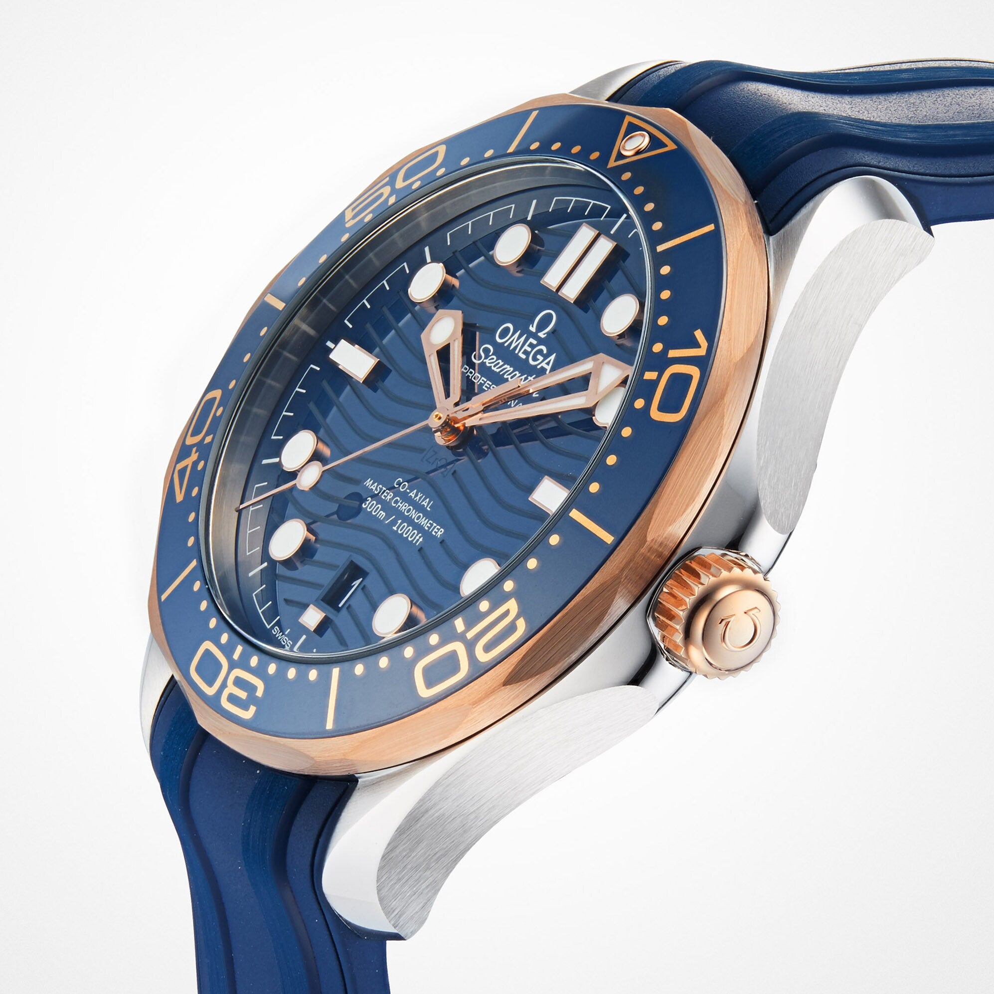 The OMEGA Seamaster Diver 300M wristwatch features a blue dial and strap, rose gold bezel and accents, and the OMEGA Co-Axial Master Chronometer Calibre 8800 movement, displayed at an angle on a white background.