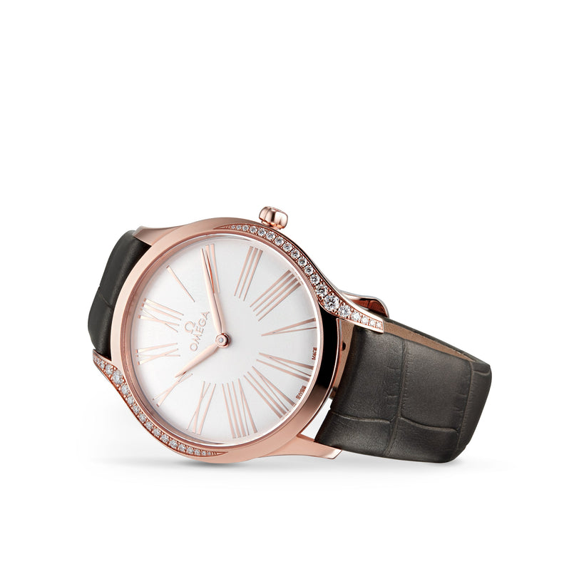The OMEGA De Ville Tresor 36 is a rose gold ladies’ watch with a white Roman numeral dial, diamond-accented case, and dark leather strap, elegantly showcased on a white background.