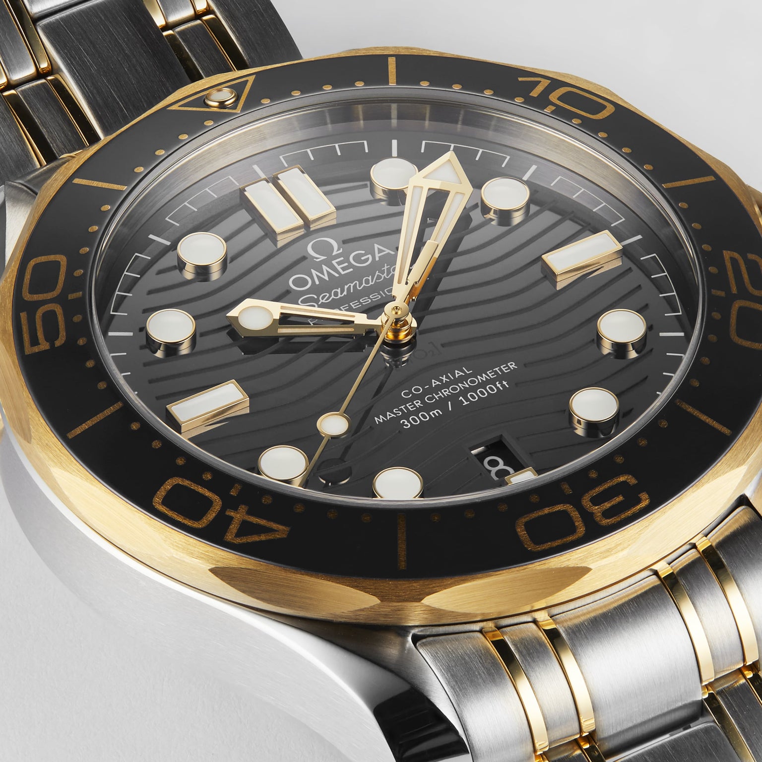 Close-up of the OMEGA Seamaster Diver 300M, showcasing a black wavy dial, gold and steel bezel, luminous hour markers, and a two-tone stainless steel and gold bracelet.