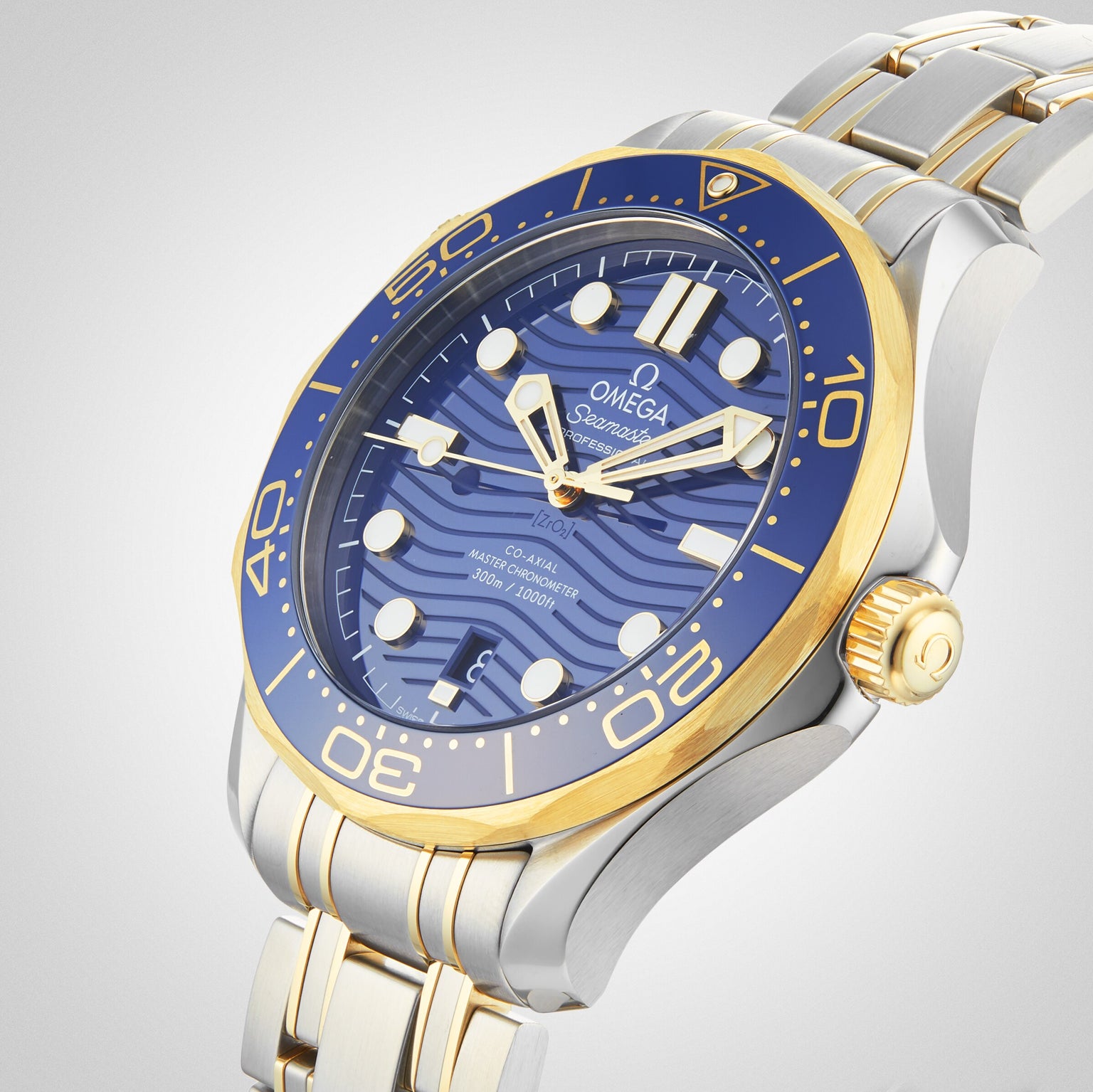 The OMEGA Seamaster Diver 300M features a blue dial and bezel, gold accents, and a stainless steel and gold bracelet, shown on a light background. Powered by the OMEGA Calibre 8800 for Master Chronometer precision.