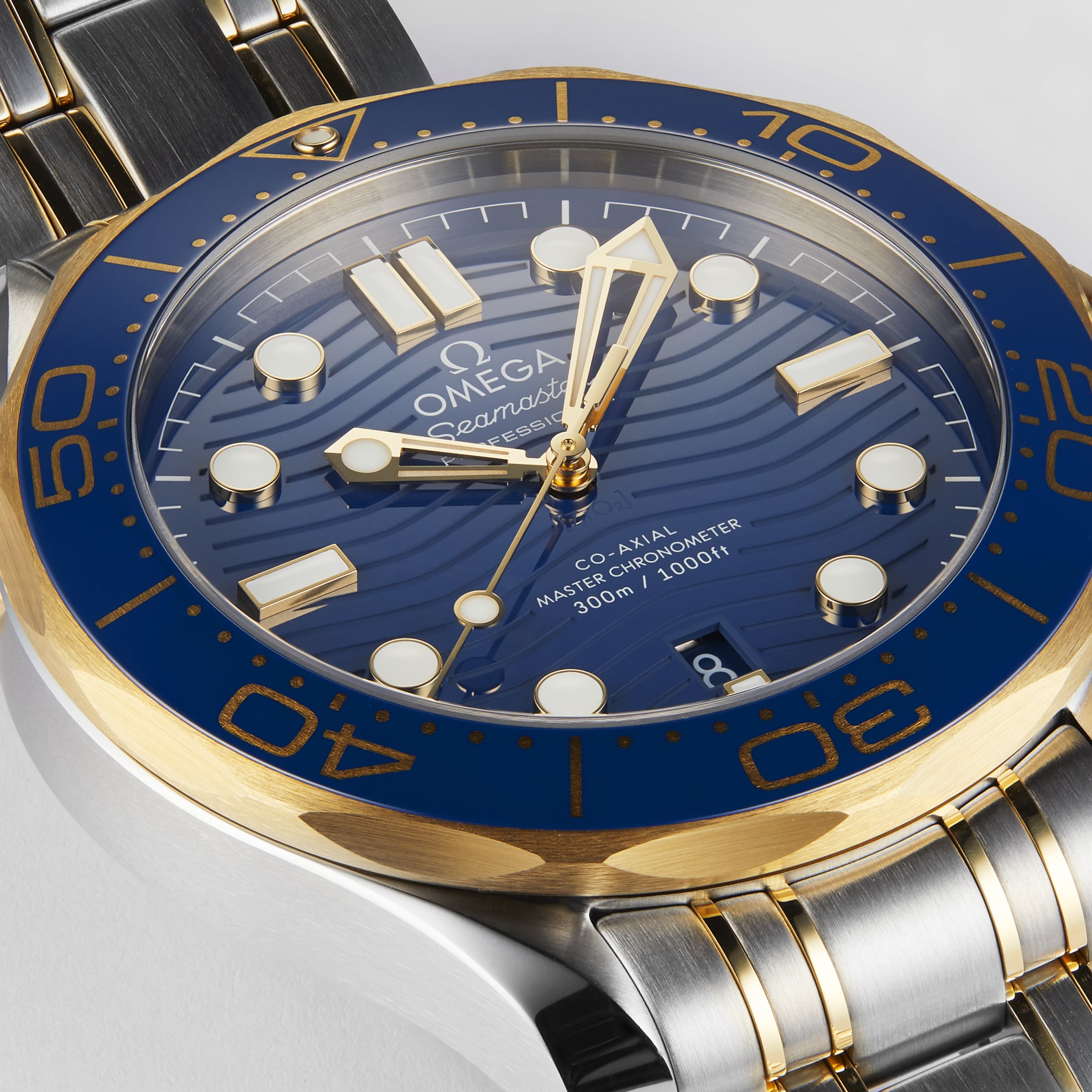 Close-up of an OMEGA Seamaster Diver 300M wristwatch with a blue dial, gold and silver bezel, and metal bracelet, displaying 10:09:12—driven by the Master Chronometer-certified movement for exceptional precision.