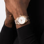 An individual in a black long-sleeve top wears an OMEGA Seamaster Aqua Terra 150M with 18K Sedna™ gold accents, a white dial, and a metal bracelet on their left wrist.