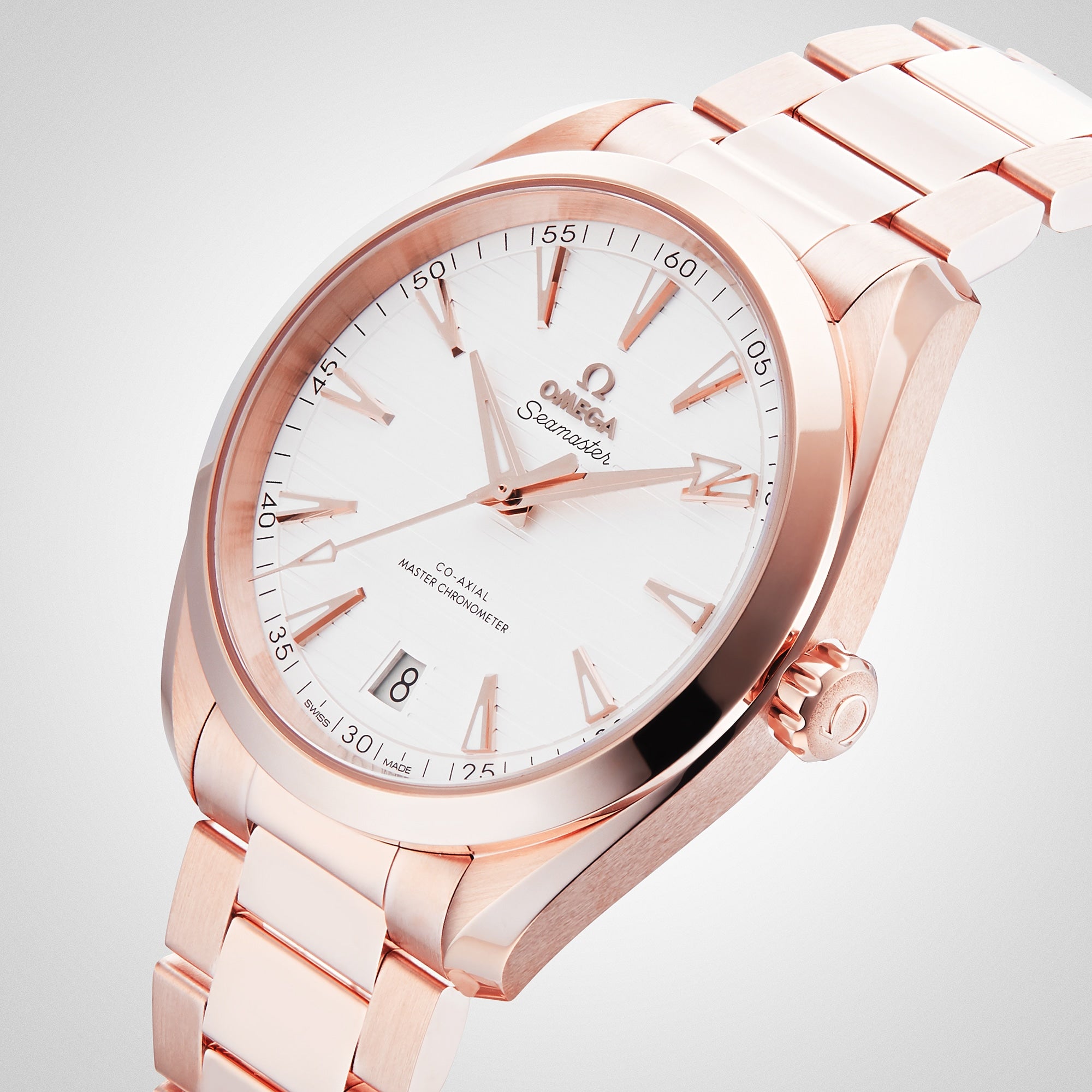 The OMEGA Seamaster Aqua Terra 150M wristwatch in 18K Sedna™ gold features a white dial, gold hour markers, a date display at 6 o’clock, and is shown on a matching metal bracelet.