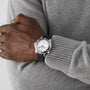 A person in a grey sweater has their arms crossed, showcasing an OMEGA Seamaster Diver 300M with a black ceramic bezel on their left wrist.