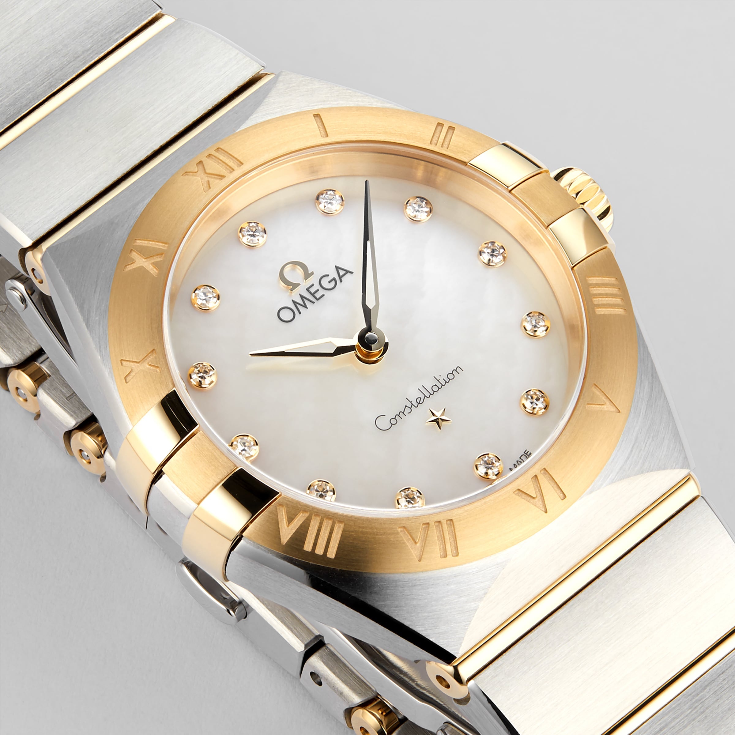 The OMEGA Constellation features a two-tone design with a mother-of-pearl dial, 18K yellow gold Roman numerals, diamond hour markers, and a stainless steel and gold bracelet—a stunning precision timepiece.