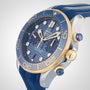 A close-up of the OMEGA Seamaster Diver 300M, featuring a blue dial, gold bezel with Ceragold™ diving scale, and a blue rubber strap, displaying markers and chronograph dials.
