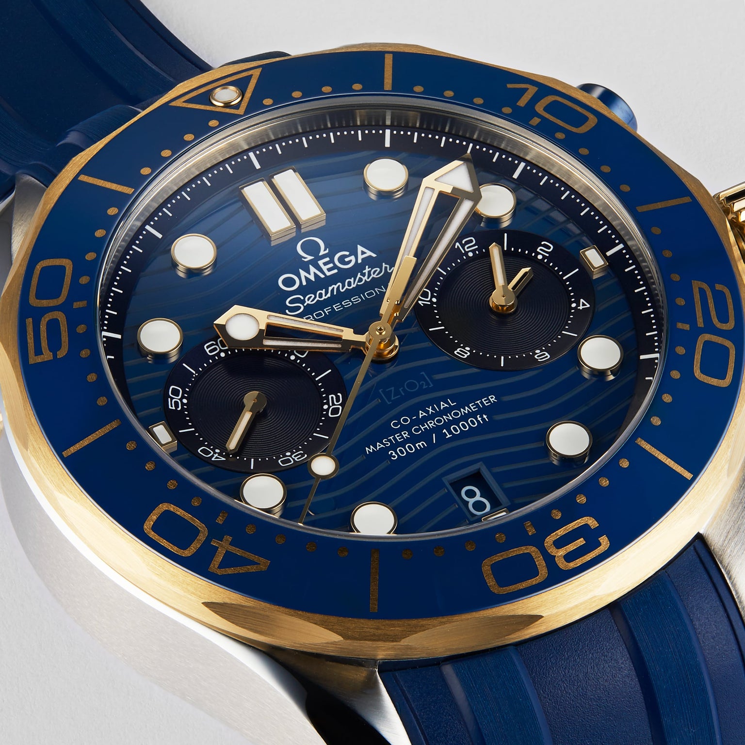 Close-up of an OMEGA Seamaster Diver 300M showing its blue dial, gold details, Ceragold™ diving scale, two subdials, blue rubber strap, and 300m water resistance indicated on the face.