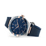 An OMEGA Constellation watch in blue and rose gold with a leather strap, blue dial, Roman numerals, and 8900 calibre movement is shown on its side against a white background.