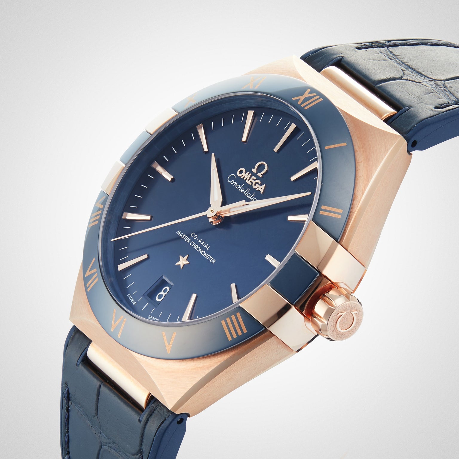 A close-up of the OMEGA Constellation watch with a blue dial, Sedna™ gold case, and blue leather strap, showcasing the 8901 calibre. The time is 10:09, and the date shown is the 8th.
