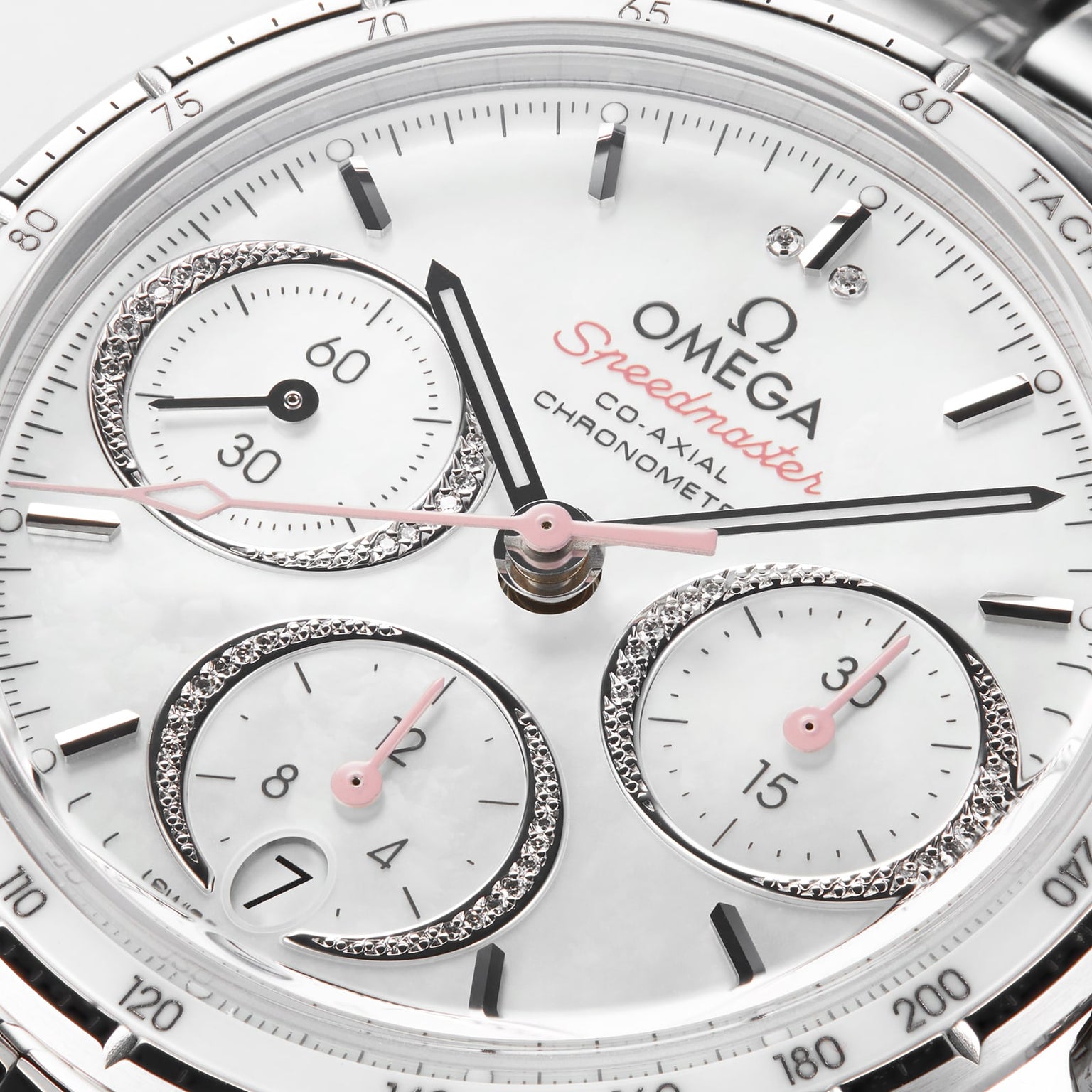 Close-up of the OMEGA Speedmaster 38 watch face, showing three subdials, diamond accents, chronograph labels, a tachymeter scale on the rim, and its precise 3330 calibre movement.