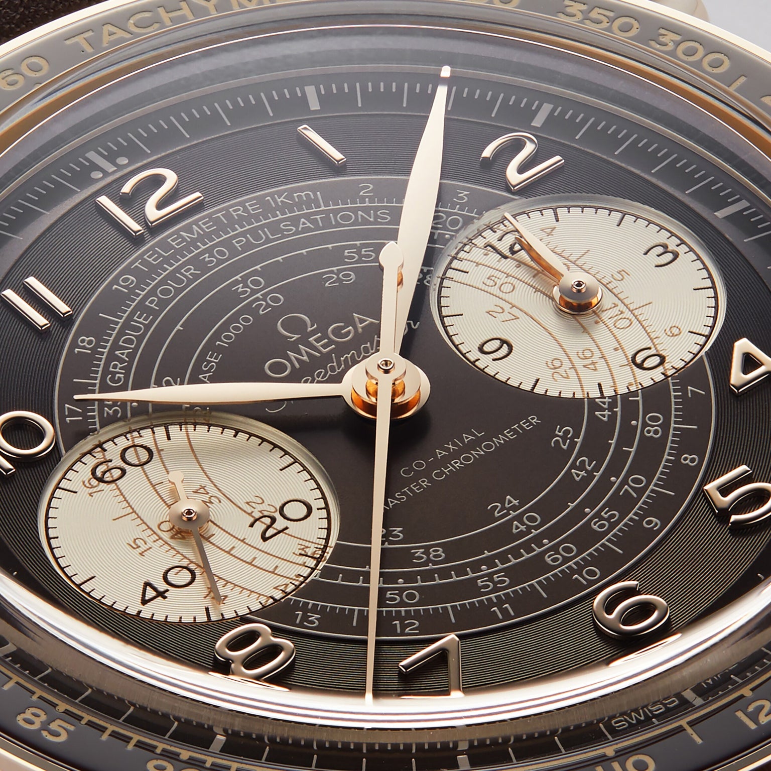 Close-up of the OMEGA Speedmaster Chronoscope dial, highlighting its three subdials, gold hands, precise markings, and a tachymeter bezel—emphasizing the watch’s vintage-inspired design.