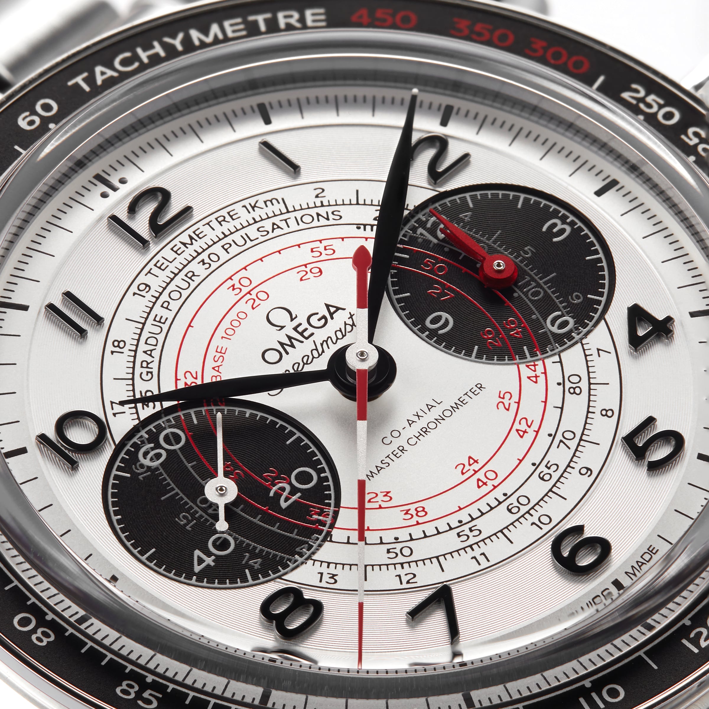 Close-up of the OMEGA Speedmaster Chronoscope watch face with black subdials, red accents, a tachymeter scale, and precise central hands displaying the time.