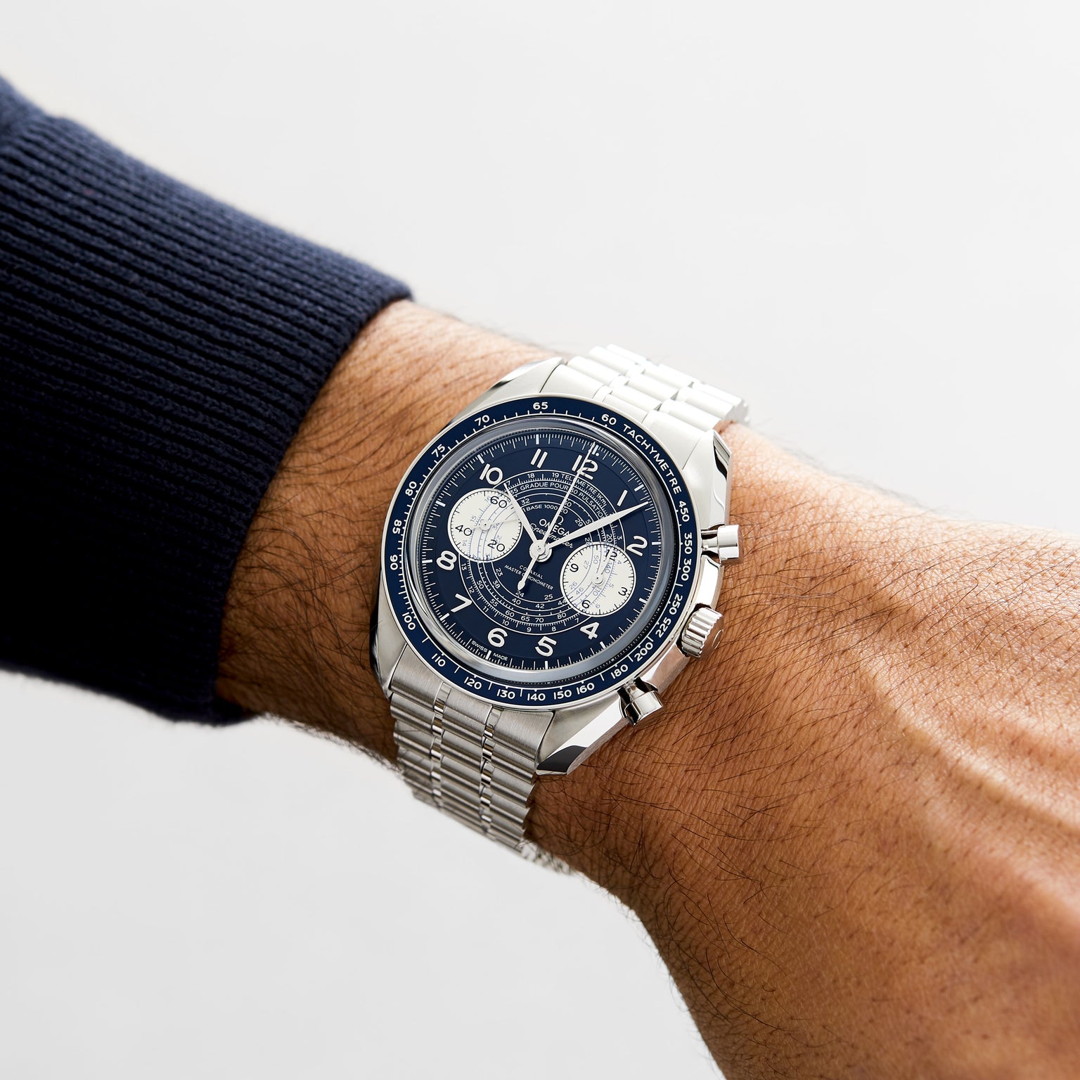 An OMEGA Speedmaster Chronoscope with a blue dial and silver strap is worn on a persons left wrist.