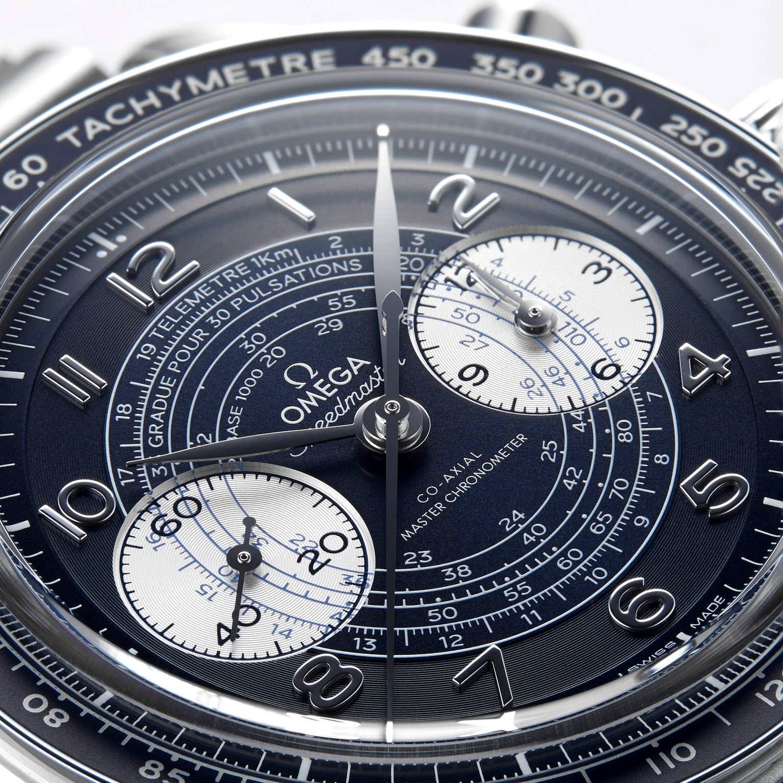 Close-up of the OMEGA Speedmaster Chronoscope wristwatch, featuring a detailed chronograph dial with silver hands, white subdials, and 9908 calibre movement set against a dark background.