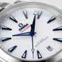 Close-up of an OMEGA Seamaster Aqua Terra 150M watch face featuring blue hour markers and hands, a white textured dial, date window at 6 o’clock, and powered by the precise calibre 8900 movement.