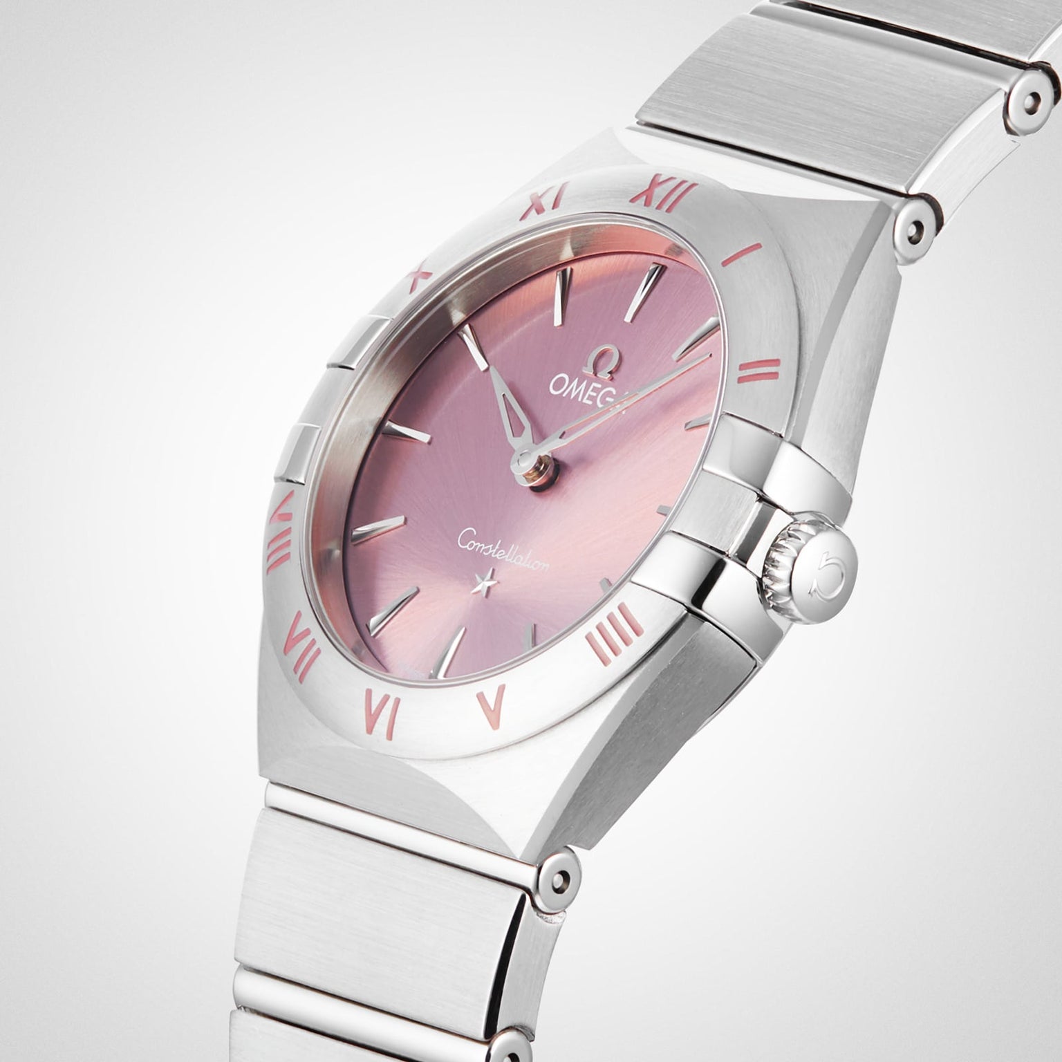 The OMEGA Constellation, featuring a stainless steel case and bracelet with a blush rose dial and pink Roman numeral markers, is displayed against a plain background.