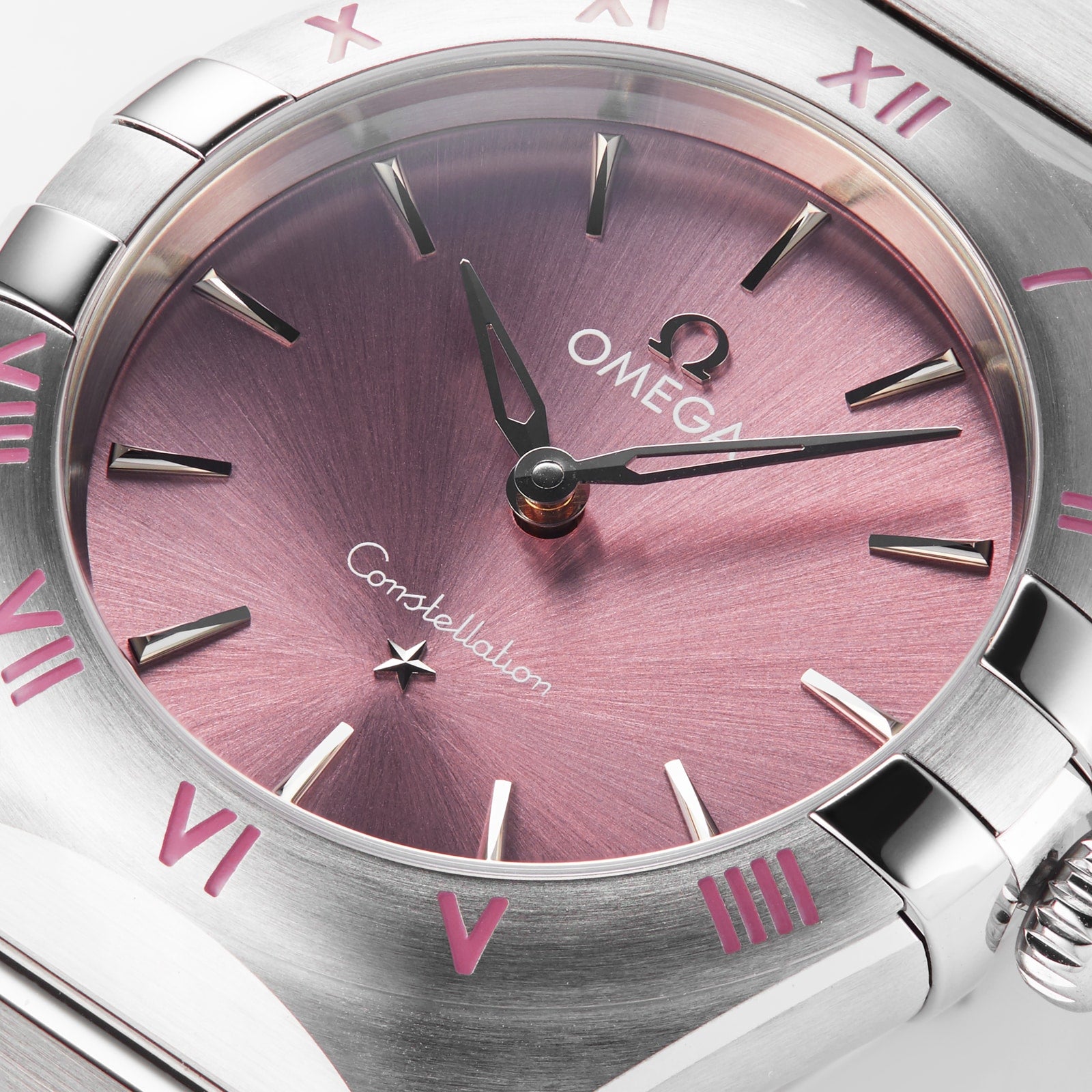 Close-up of the OMEGA Constellation watch with a blush rose sunburst dial, silver hands, Roman numerals, and a brushed stainless steel case and bracelet.